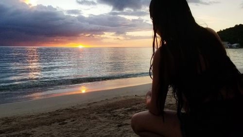 Woman looking at sea against sky during sunset