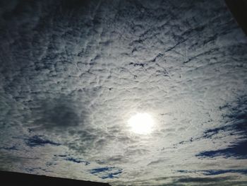 Low angle view of sun shining through clouds