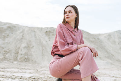 Fashion beauty portrait of young woman in pink organic velvet shirt on desert background