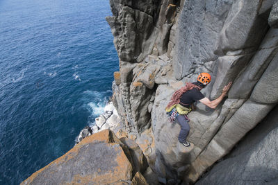 Man standing on rock by sea