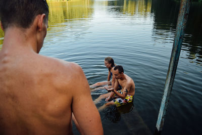 Rear view of shirtless man in lake