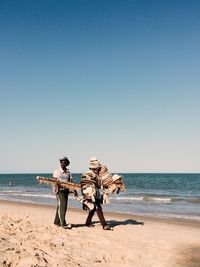 Vendors selling hats and jewelries at beach against clear blue sky