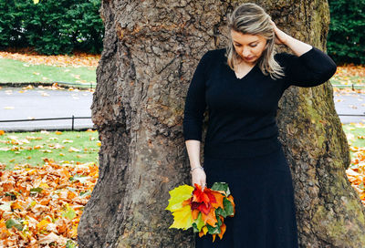 Young woman with flowers on tree trunk