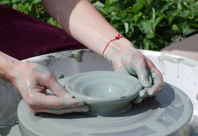 Ceramic workshop - the girl makes a pot of clay on a potter's wheel. hands closeup.