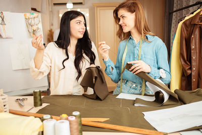 Women seamstresses sweep away, sew fabric, details of future clothes. happy, smiling. fashionable 