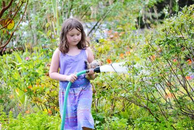 Girl watering plants in yard