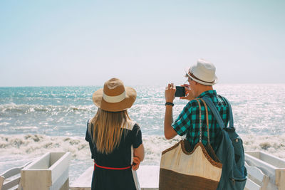 Rear view of people looking at sea against clear sky