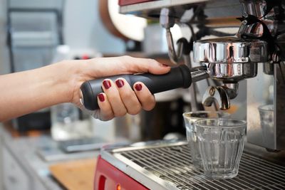 Cropped image of hand holding coffee cup at cafe