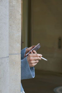 Close-up hand of woman holding smart phone and cigarette