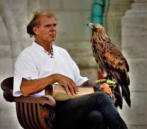 Man with golden eagle sitting on chair