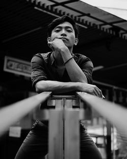 Low angle portrait of young man standing by railing