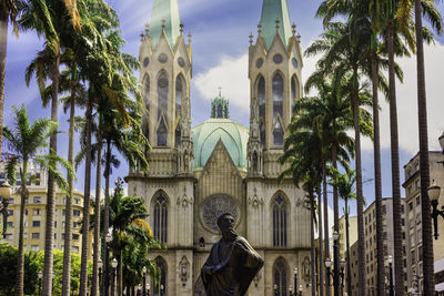 Panoramic view of building and palm trees against sky