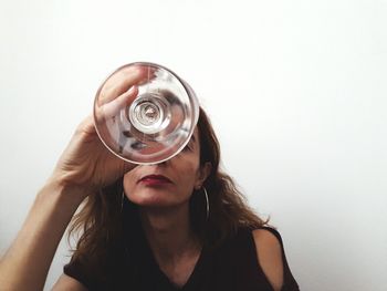 Portrait of woman holding glass against white background