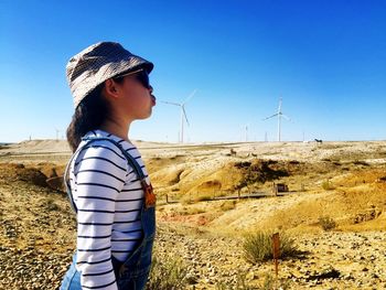 Optical illusion of girl blowing windmill while standing on land