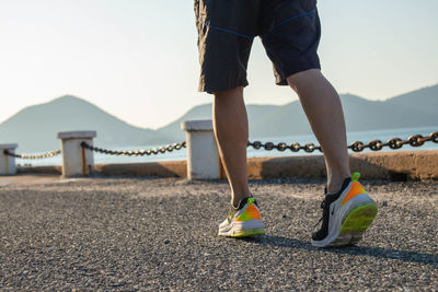 Low section of woman standing on mountain against sky
