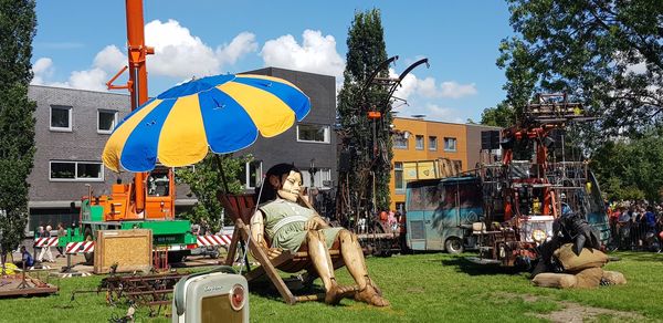 People sitting by buildings against sky in city