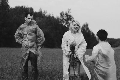 Portrait of friends standing on field against sky