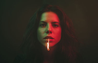 Portrait of young woman against black background