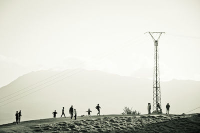 People on mountain against clear sky