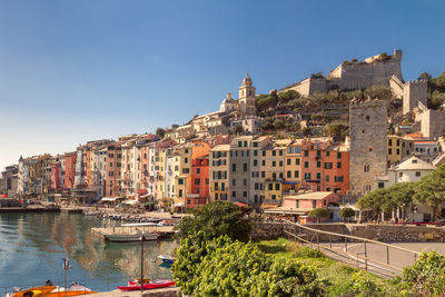 Buildings by river against clear sky in city