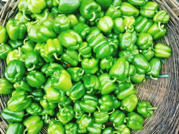 Directly above view of green bell peppers in wicker basket for sale