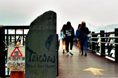 Rear view of people on railing against sky