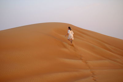 Rear view of woman walking on sand