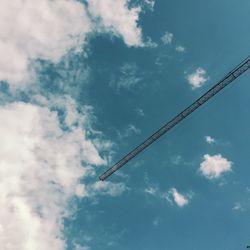 Low angle view of crane against cloudy blue sky