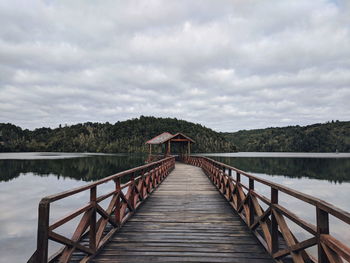 Footbridge over lake against sky