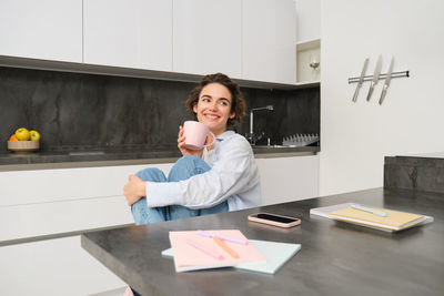 Portrait of young woman using digital tablet while sitting on table