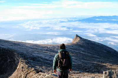 Rear view of woman standing on mountain against sky