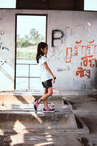 Side view of girl walking against wall