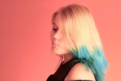 Close-up of girl with dyed hair against red background