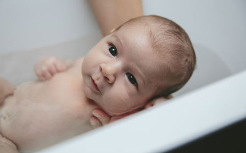 Cropped hands of mother bathing baby girl in bathtub