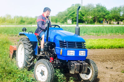 A farmer drives a tractor while working on a farm field. loosening surface, cultivating the land