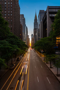 Road amidst buildings in city against sky