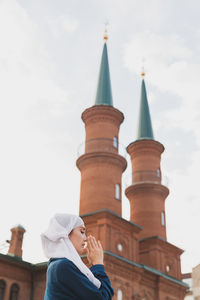 Low angle view of woman praying against mosque