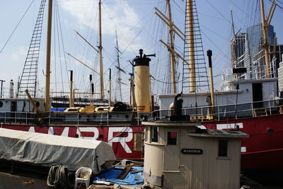 Sailboats moored in harbor by buildings against sky