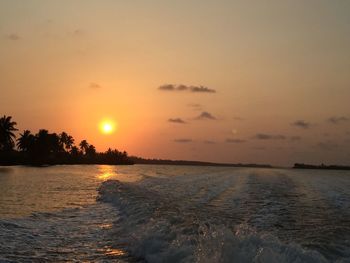 Wake on lake against sky during sunset