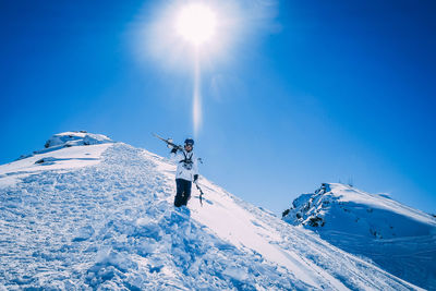 Man skiing on snowcapped mountain against sky