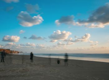 People on beach against sky during sunset