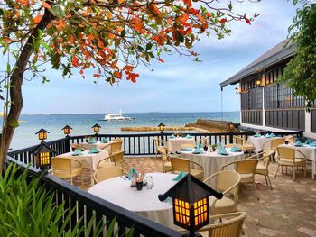 Chairs and tables at beach against sky