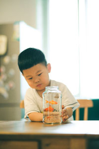 Boy drinking glass on table