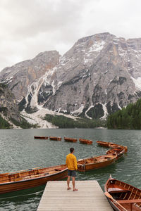 Rear view of man on boat in lake against mountains