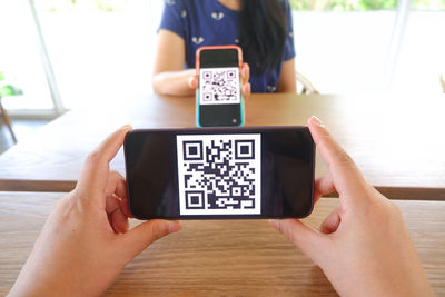 Low section of person photographing with smart phone on table