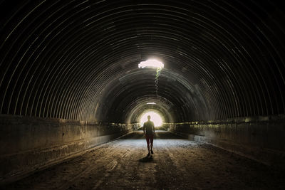 Rear view of man walking in tunnel