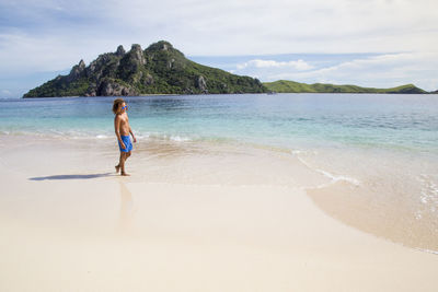 Rear view of woman on beach against sky