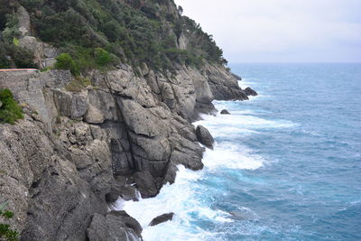 Rock formation on sea shore against sky