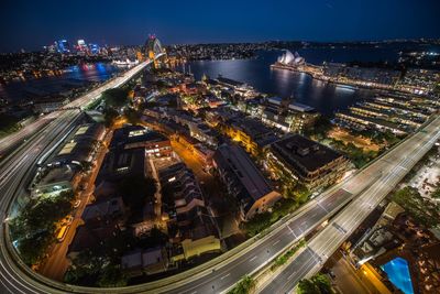 High angle view of illuminated street amidst buildings in city at night