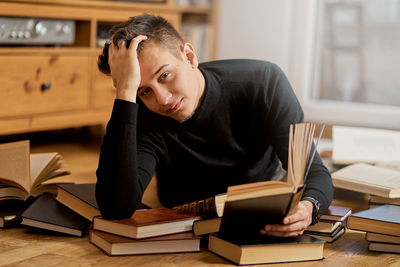 Portrait of man with book lying on floor at home